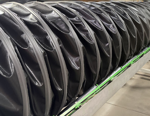 Black flexible hi-temp ventilation duct with reinforced wear strips and spiral support construction during manufacturing